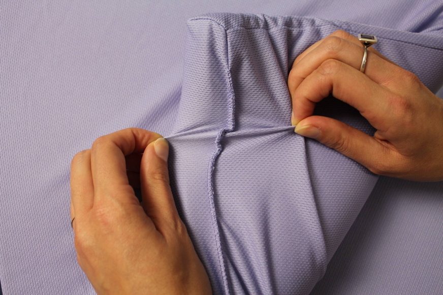 Mãos a segurar numa camada interior de uma almofada, envolta em tecido roxo, para mostrar os acabamentos